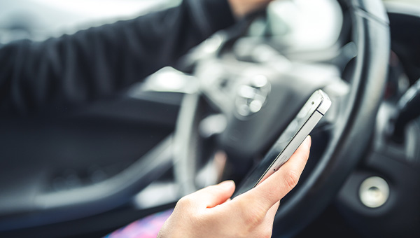 A picture of someone using a cell phone while driving.