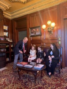A picture of Senator Argall showing a photo of his father, a school librarian, to a the PA Literacy Coalition group that visited his Capitol office.