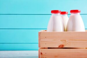 A picture of bottled milk in a wooden milk crate.