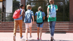 4 kids with bookbags walking to school