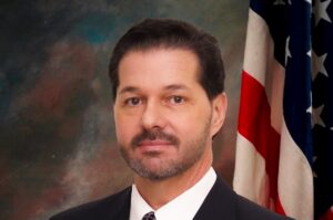 A headshot of Bruce Nalesnik in front of an American flag.