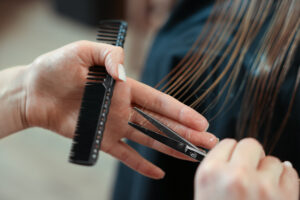 Professional hairdresser cutting girl's hair in beauty salon, closeup