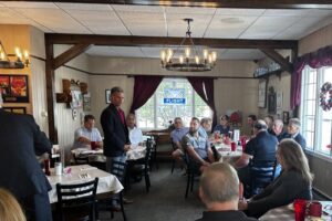 Congressman Dan Meuser speaks to a crowded room of people in a restaurant.