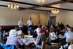 Senator Argall and Representative Jamie Barton speak to a crowded room of people in a restaurant.