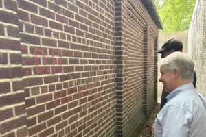 Senator Argall inspects a message supporting President Franklin D. Roosevelt on a historic building.