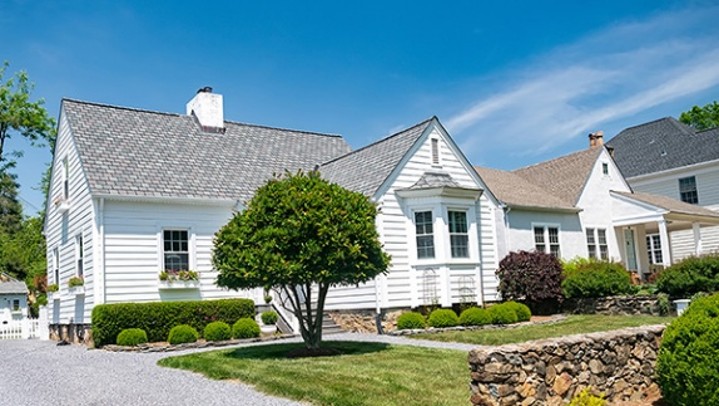 An exterior shot of a white house in a suburban neighborhood.