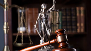 A gavel, figure of Lady Justice and scales sit in front of a bookshelf.