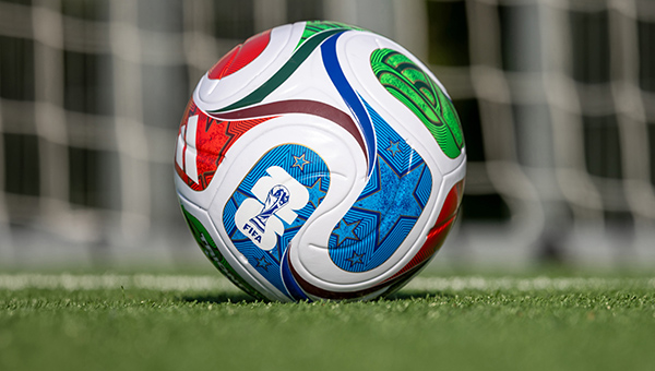 A soccer ball with FIFA World Cup branding sits on a grassy field.