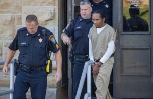 Michael Bon being escorted out of a hearing.