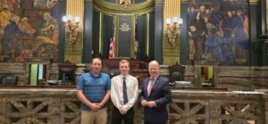 A picture of Sen. Argall’s job shadow, Bradley Barlett and his father with the Senator in the Senate Chamber.